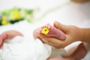 lady hold the foot of a baby, yellow flower on foot