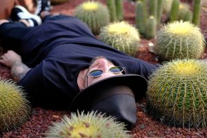 man it hat laying in field of cacti