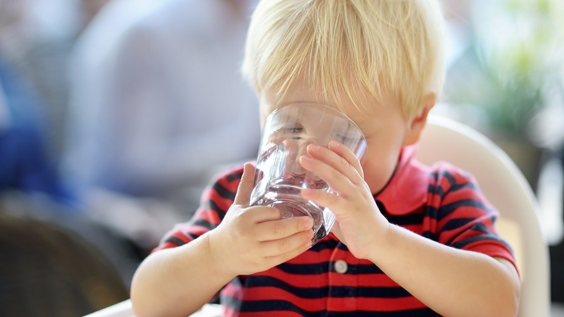 toddler drinking water from a glass
