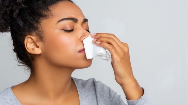 lady with tissue under nose catching nose bleed