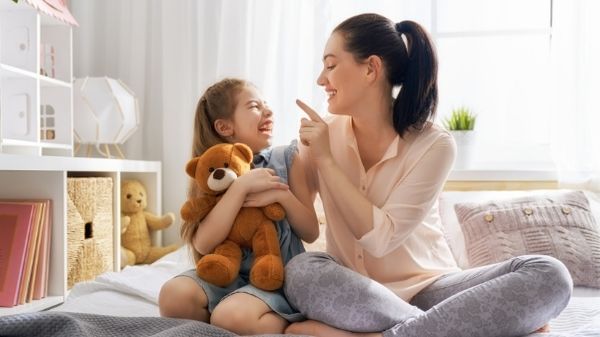 mom talking to daughter on bed