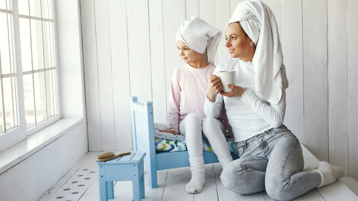 mom and daughter sitting on bed with towels on their heads relaxing