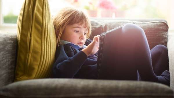 young girl watching tablet on sofa