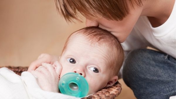 sibling kissing baby on head