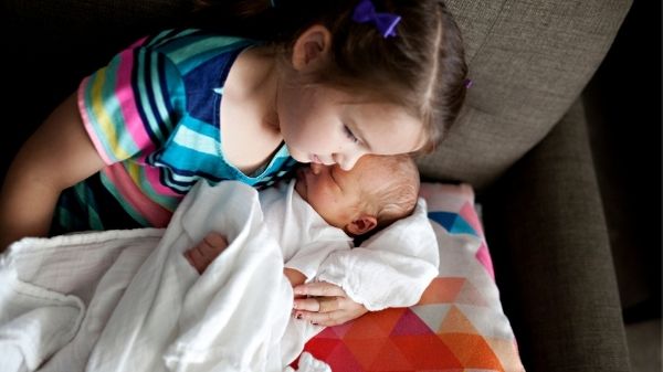 sibling with baby on couch