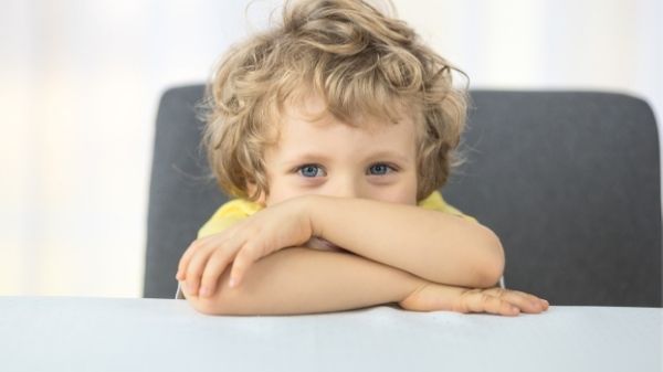 3 year old sitting at desk looking at camera