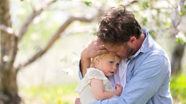 dad hugging toddler girl in woodland