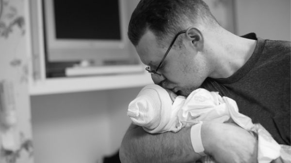 dad kissing newborn baby