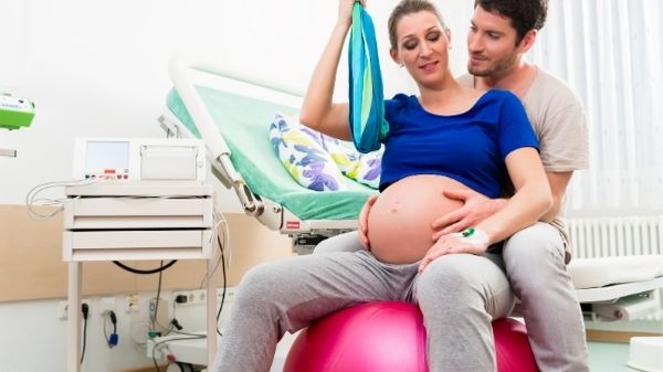 labor lady bouncing on exercise ball with dad supporting