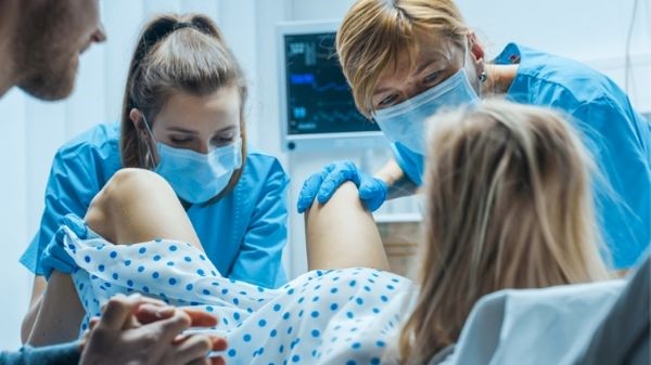 lady giving birth with dad and 2 midwives