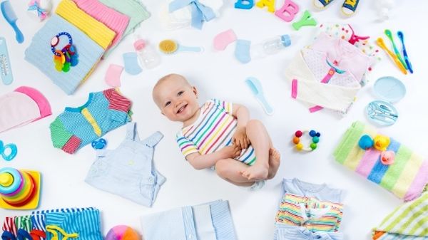 baby on the floor with lots of clothes