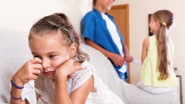 girl jealous of her old siblings crying on sofa