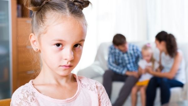 sad girl jealous of parents speaking with older child