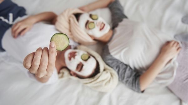 two women on a bed with face masks on