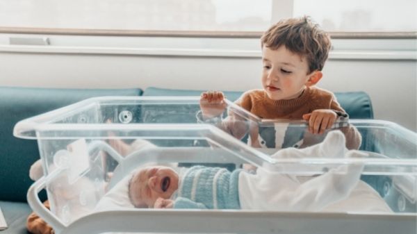 toddler watching over his baby sibling