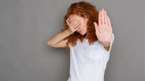woman saying stop with hands whilst covering her face