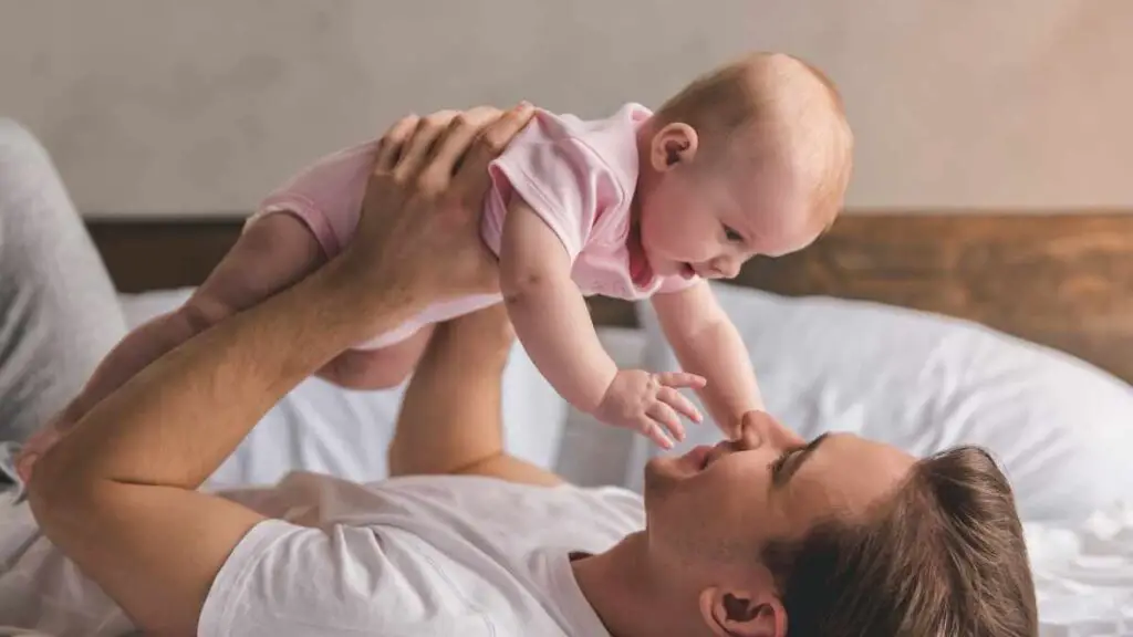 dad holding baby above bed