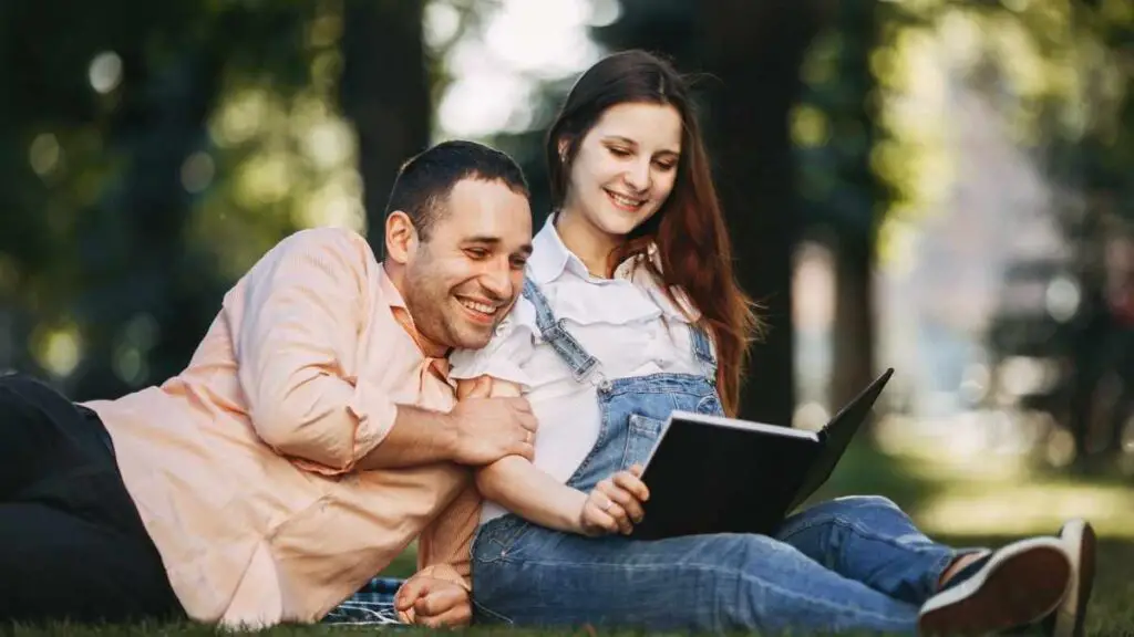 dad reading to pregnant mom in the woodland