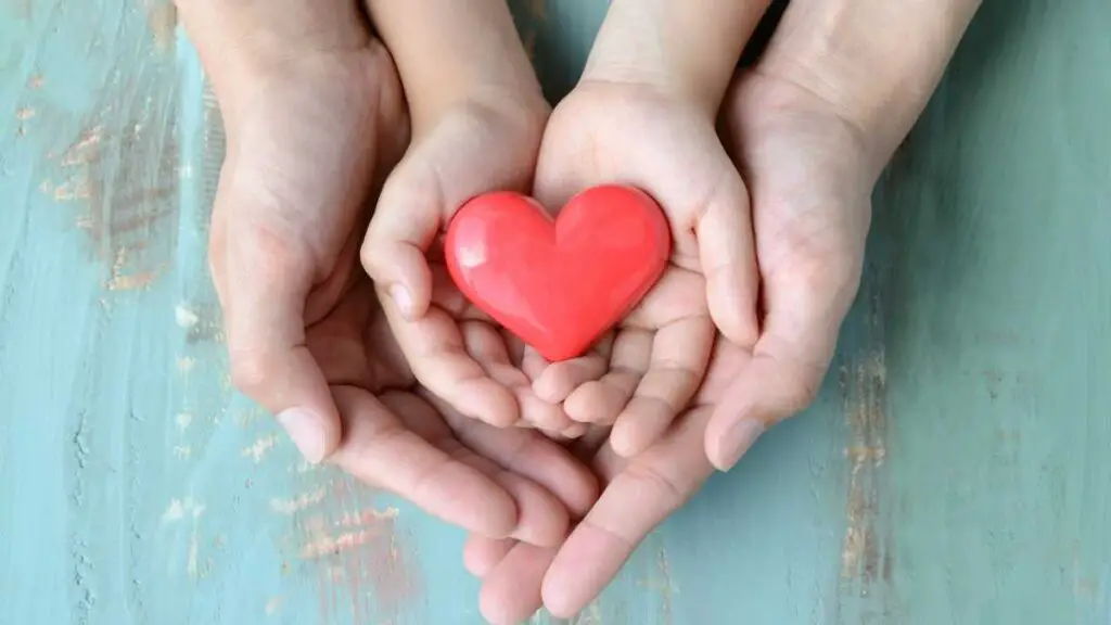 kids hands in adult hands holding heart