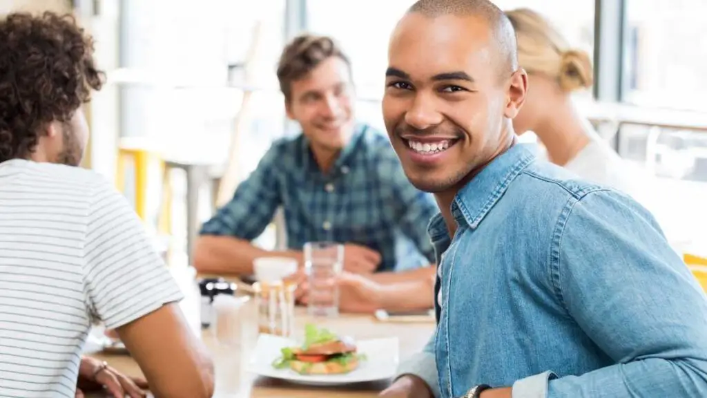 man out with friends socializing at a table eating lunch