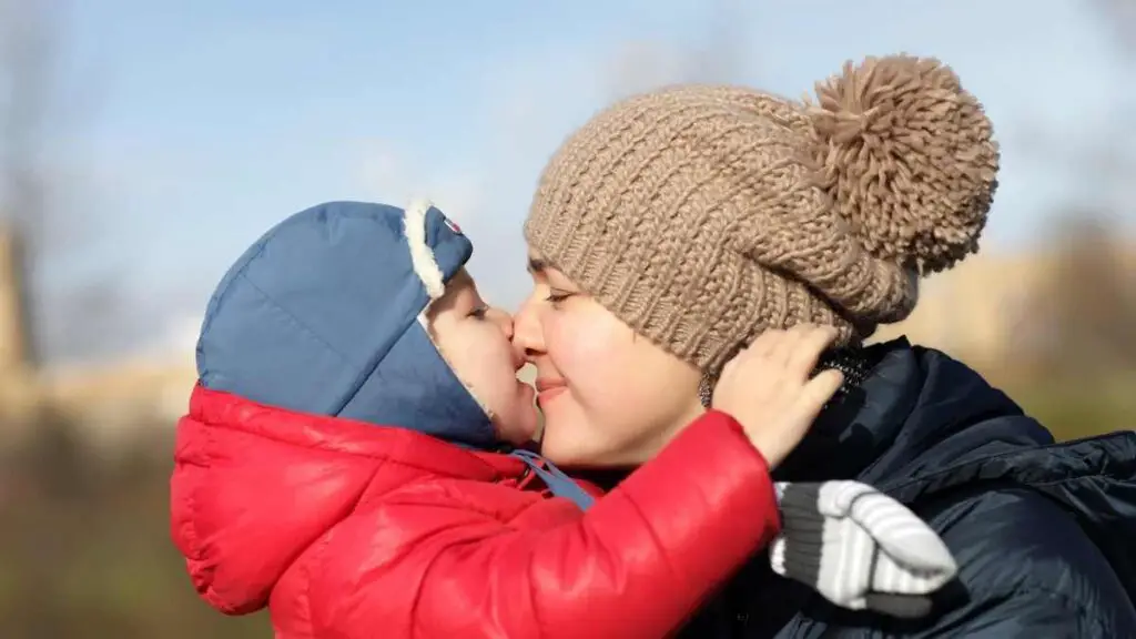 toddler kissing mom outside