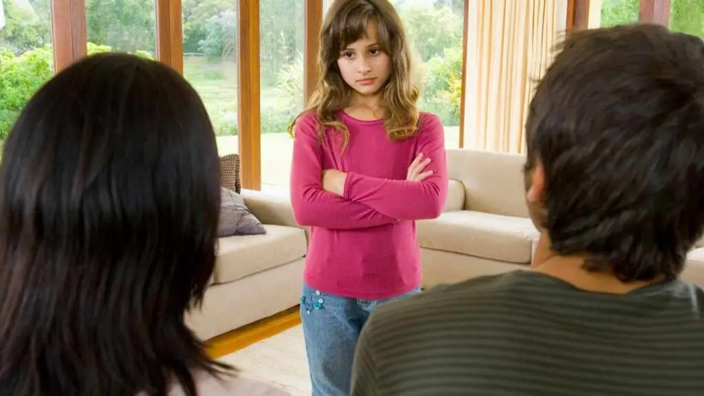 girl standing in front of parents with arms crossed