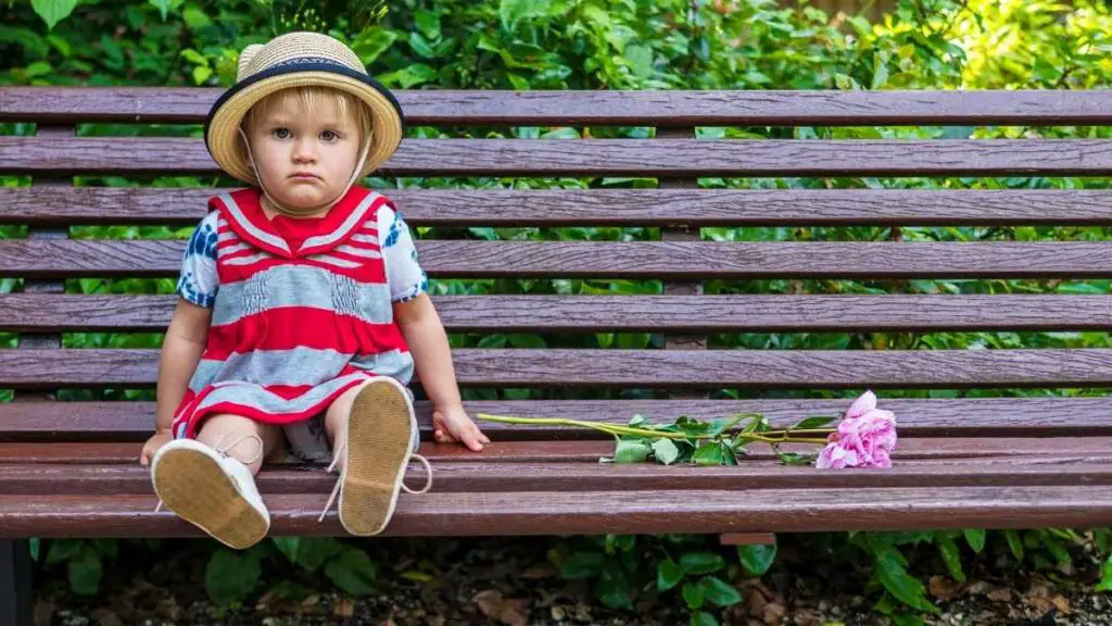 toddler looking sad on bench with flower