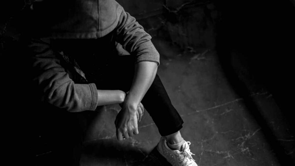 teenager in shade sitting on floor